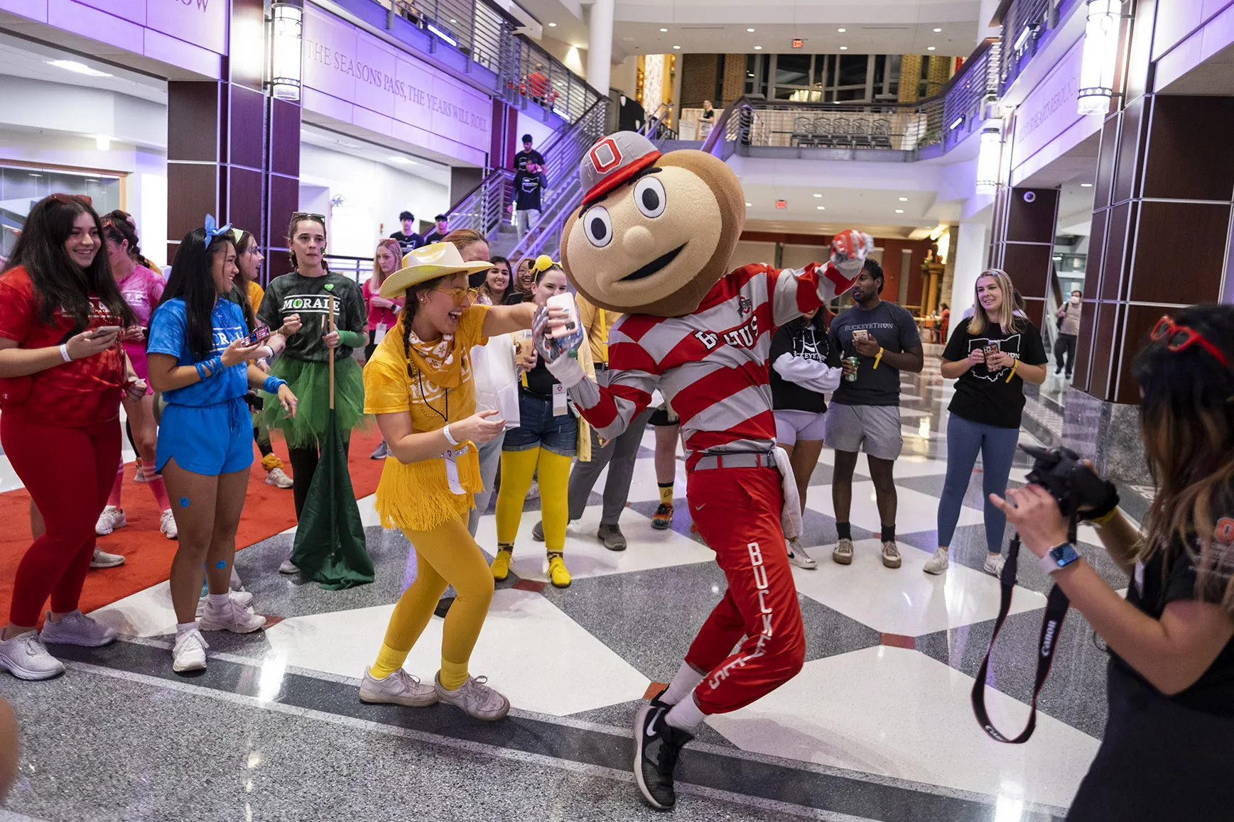 Brutus dances in the student union with brightly dressed students