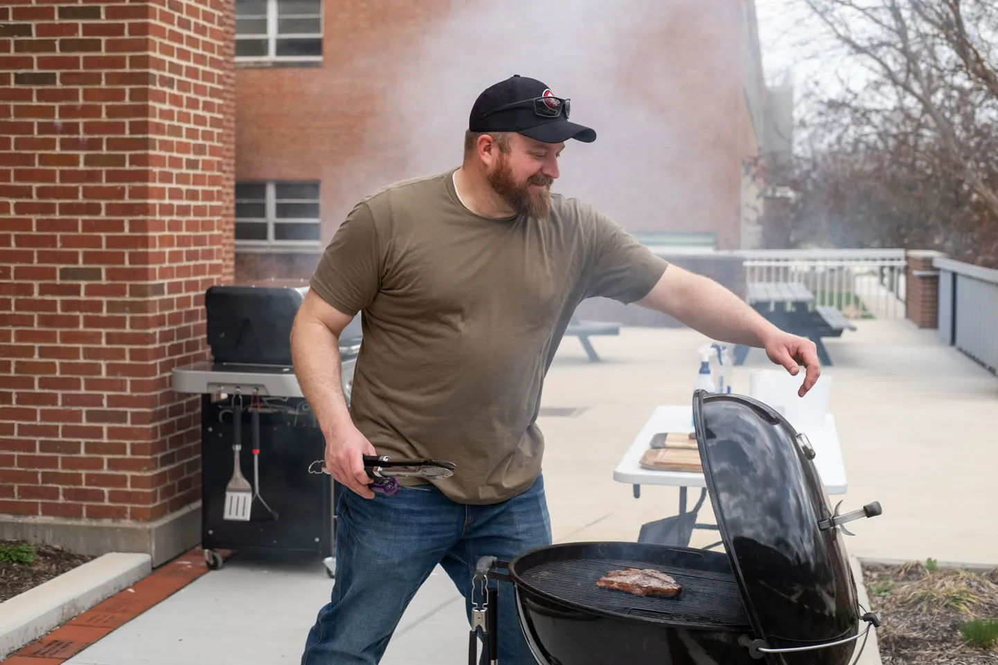 Cressman cooks a piece of steak on a charcoal grill outside on Ohio State's campus