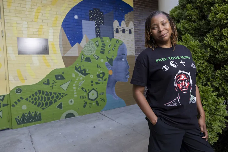 April Sunami smiles knowingly as she poses in front of a colorful mural she painted