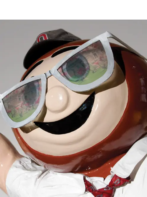 A statue of the Ohio State mascot, Brutus Buckeye, wearing an OSU ball call and large sunglasses. 