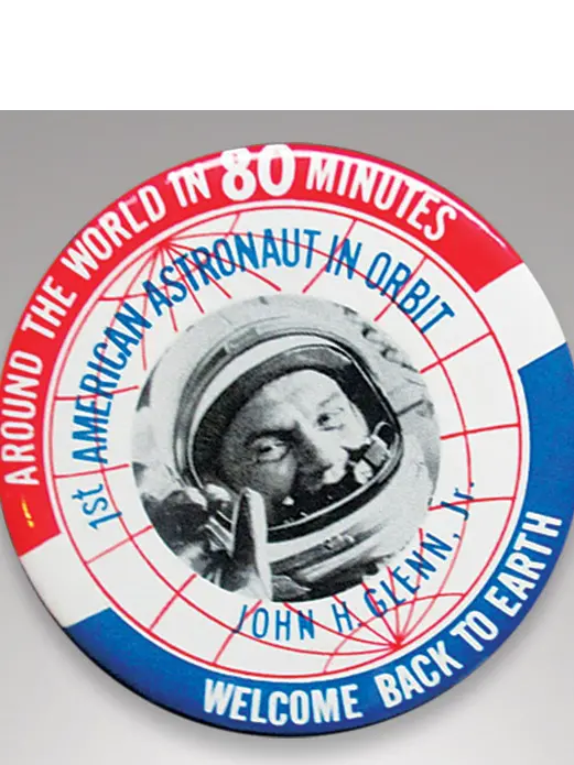 A circular red, white, and blue button with a black and white photo of John Glenn in his space helmet.