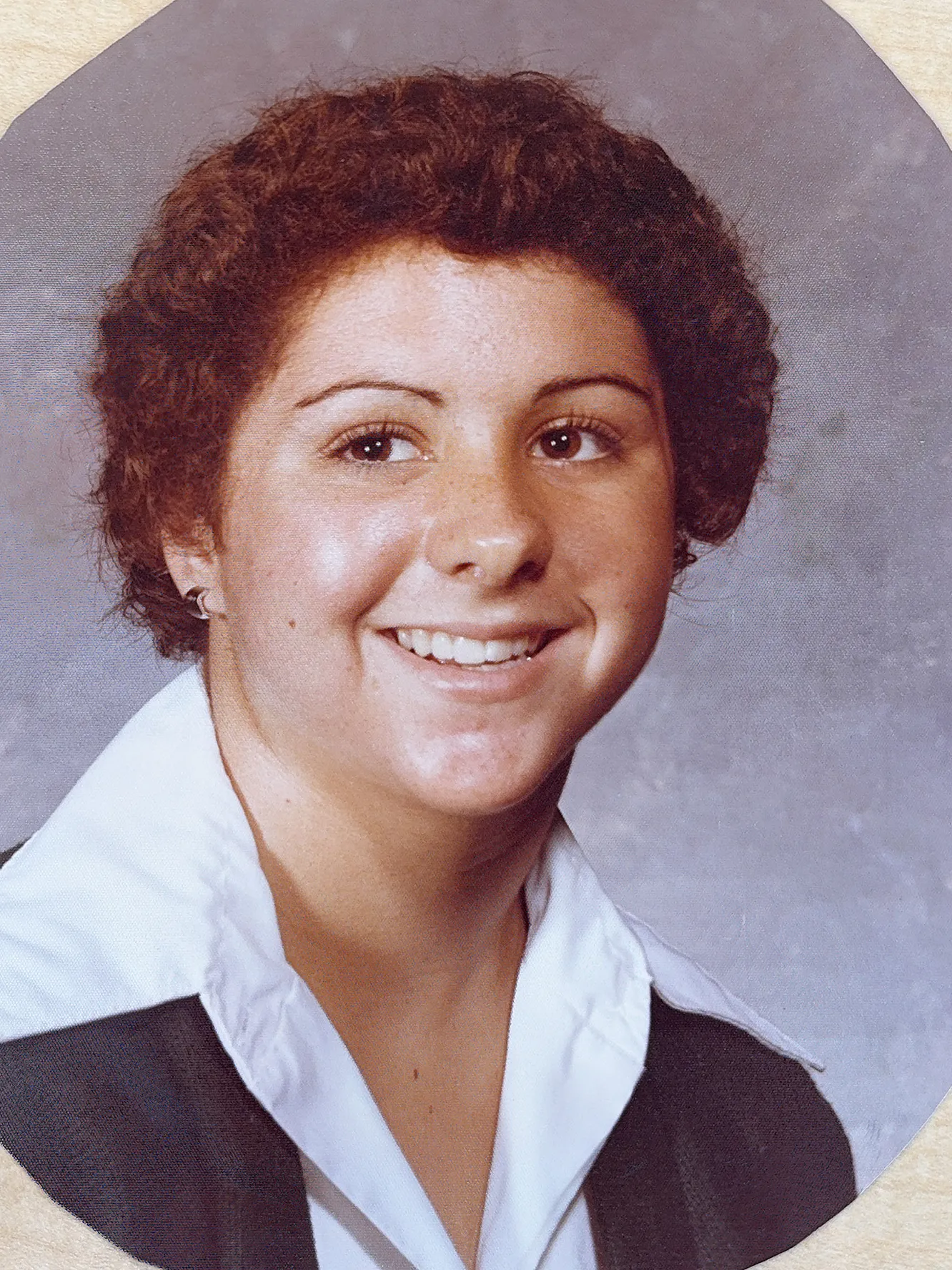Molly in a high school portrait has short curly hair and a wide-collared shirt