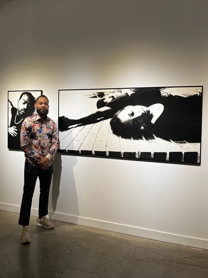 Banner is photographed in front of giant black and white photos of people lying on the ground, as if dead or sleeping.