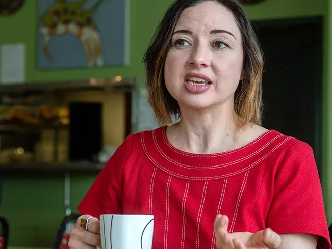 Portrait of Paloma Martinez-Cruz in a red shirt having coffee or tea