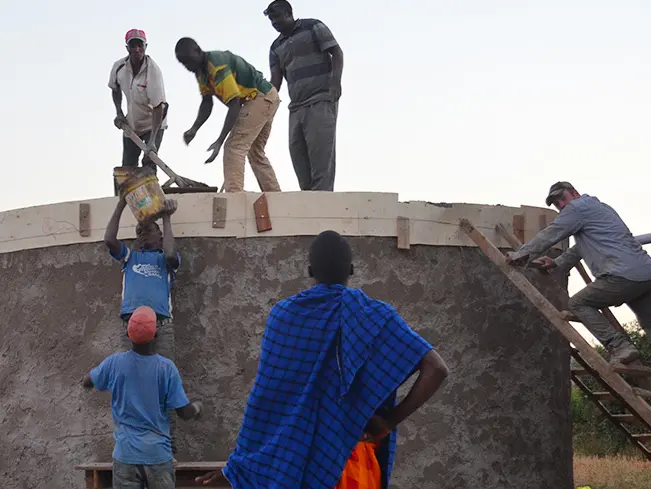 Ohio State students and community members from Tanzania install the roof of a rain-water harvesting tank