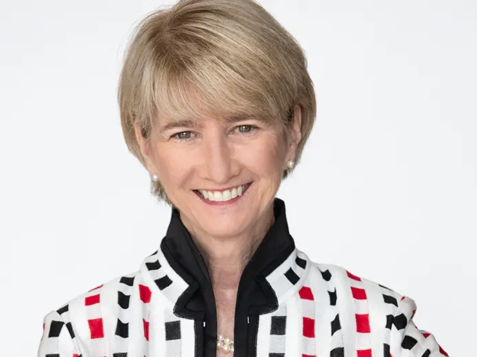 Ohio State President Kristina M. Johnson, a white woman with short blond hair, smiles warmly and wears a suit in this shot of her head and shoulders