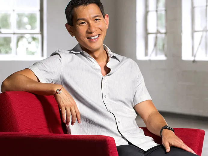 Chris Pan sits in an armchair laughing