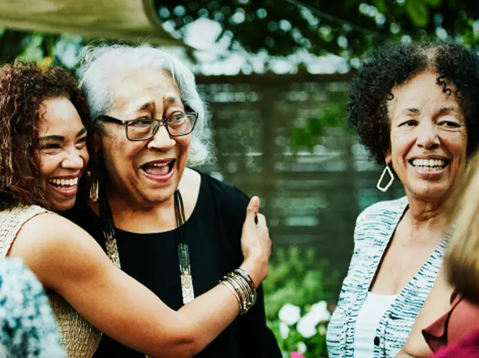 A young woman is hugging an older woman while standing with a group.