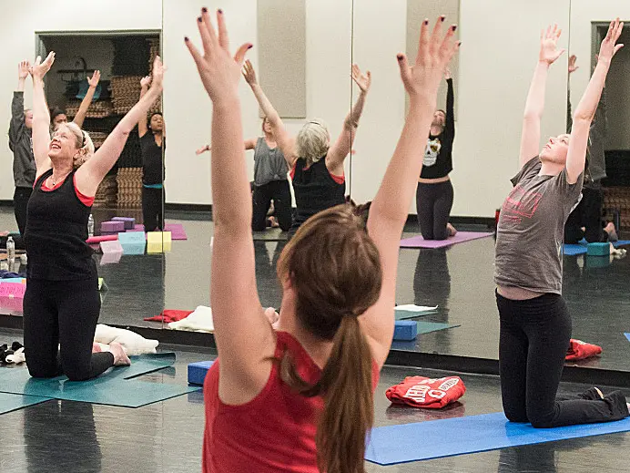 group of people doing yoga in a studio with their arms in the air
