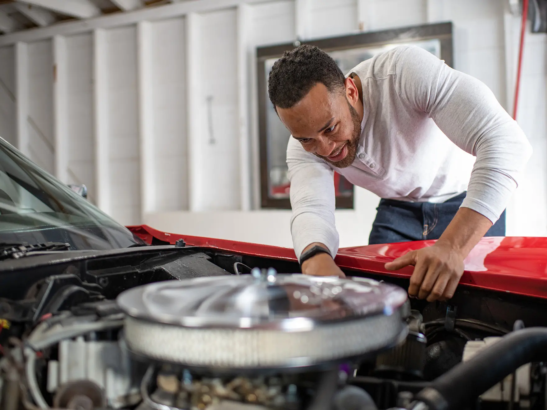 Charles Muse working on engine of red Corvette