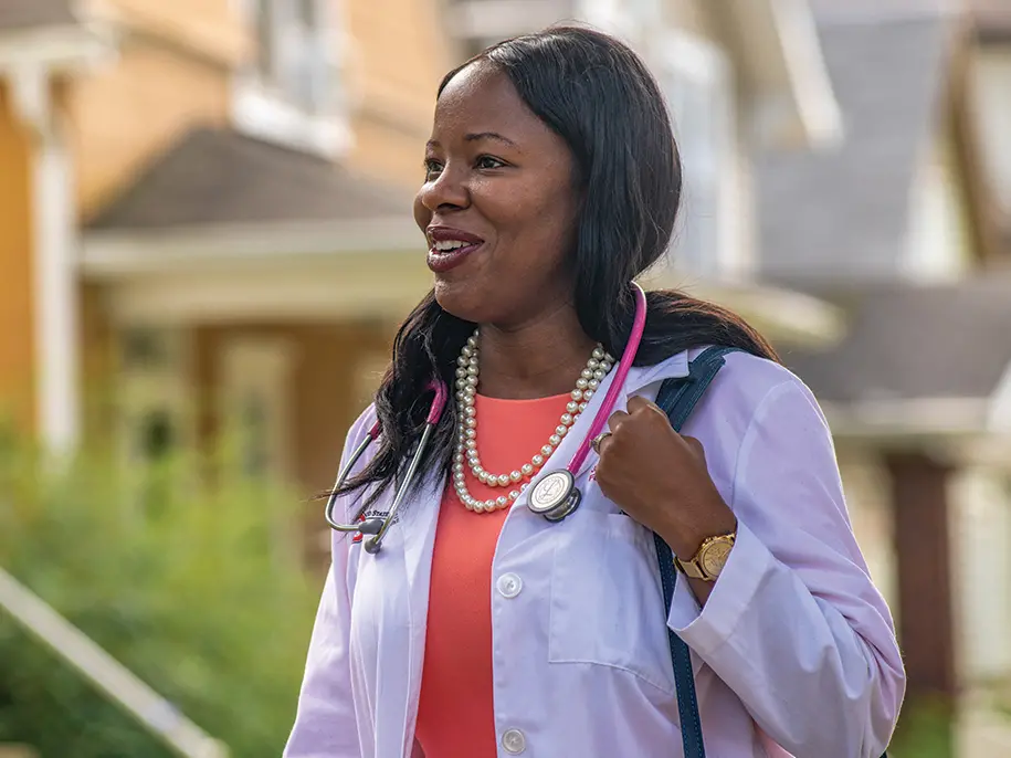 Dr. Olayiwola, a Black women with long hair in a white coat and a stethoscope around her neck, Dr. J. Nwando Olayiwola