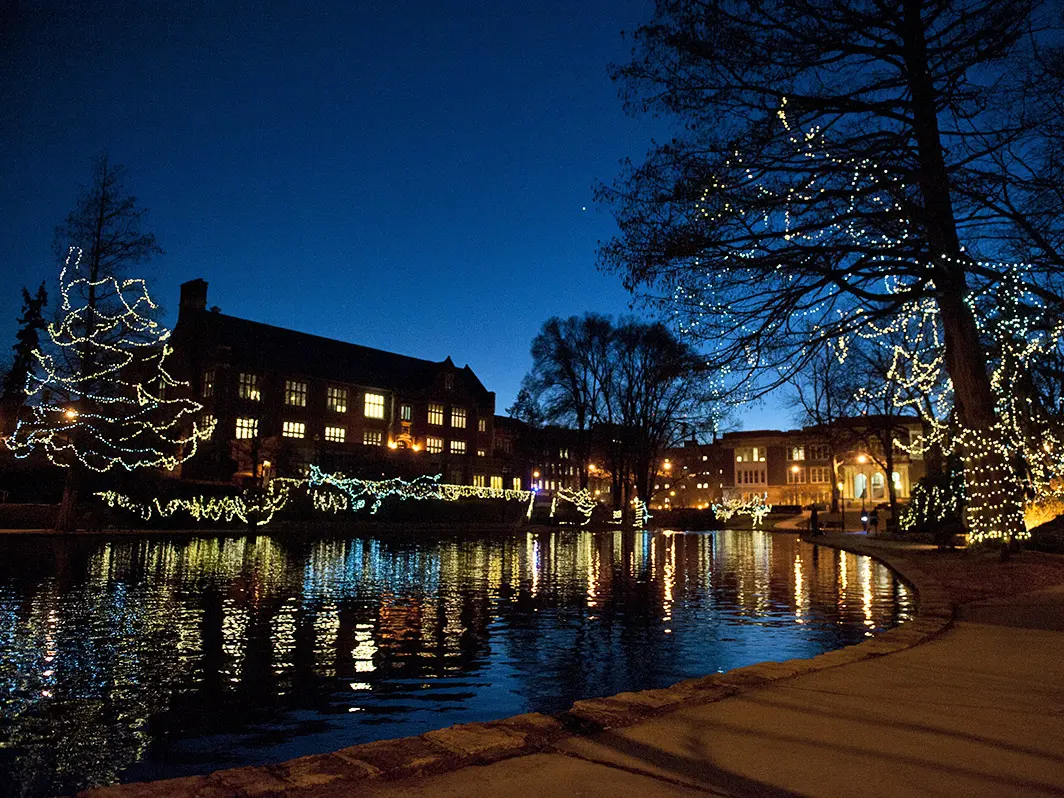 A winter night scene at Mirror Lake with snow on the ground and string lights in the trees.