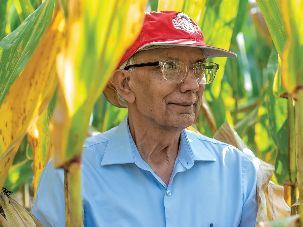 Rattan Lal stands in a field of corn wearing a red baseball hat