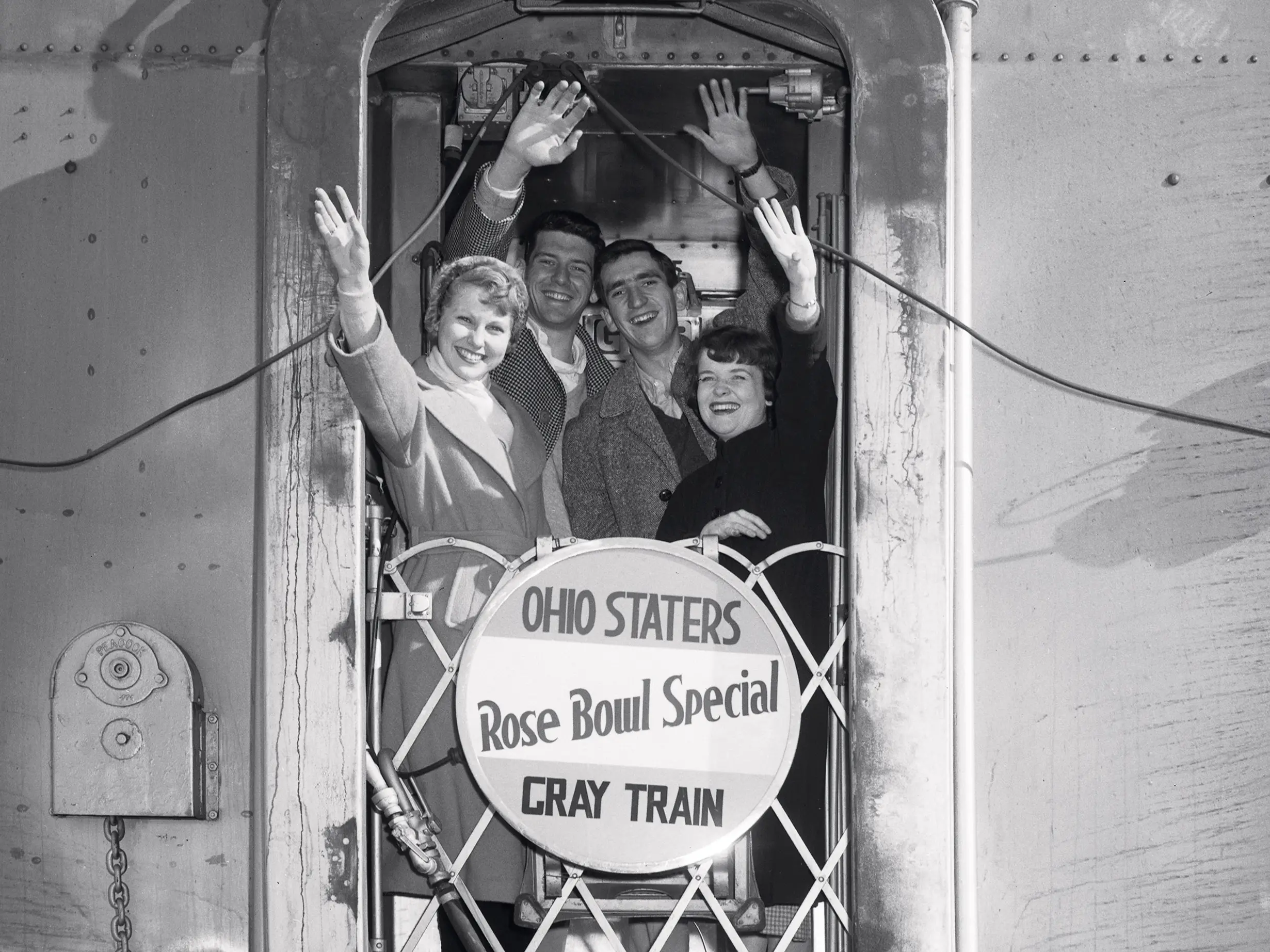 People wave from the back of a train