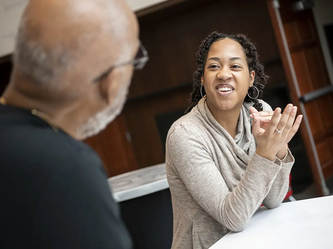 A young Black woman smiles at the fellow scientist who funded her scholarship