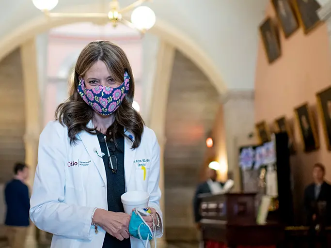A smiling woman wearing a surgical mask