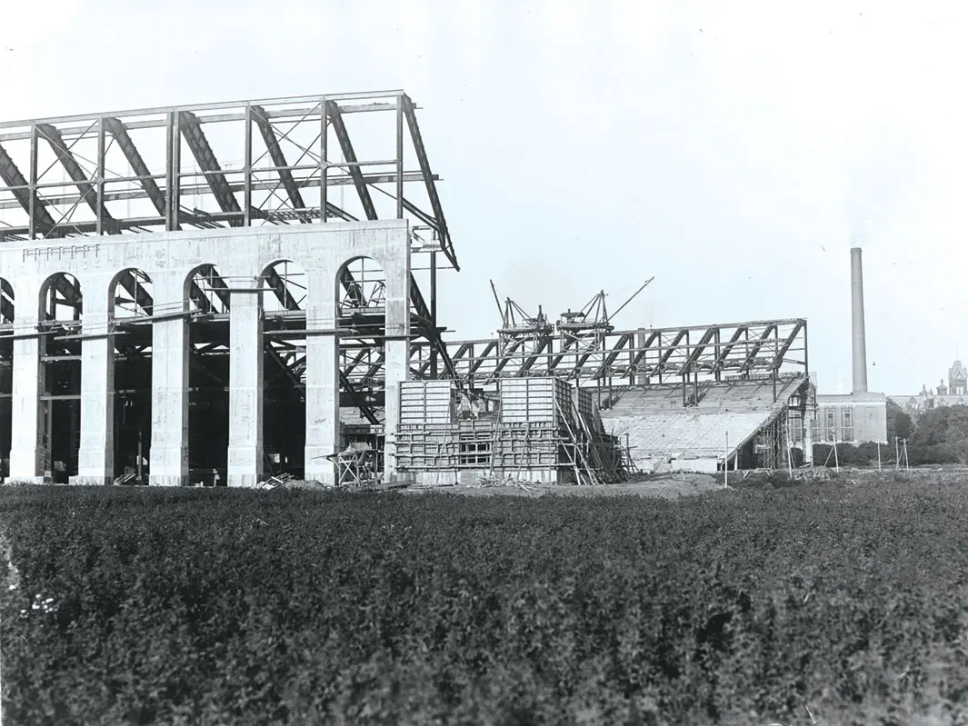 An old black and white photo taken from the west side of the stadium shows some exterior arch work completed and the skeleton of what will become the upper deck of stands.