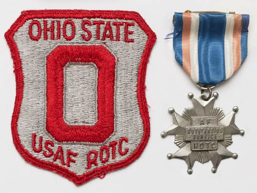 The red and gray patch says Ohio State USAF ROTC and features a block O. The star-shaped medal hangs from a blue, peach and white ribbon and says AF ROTC Outstanding Service. 