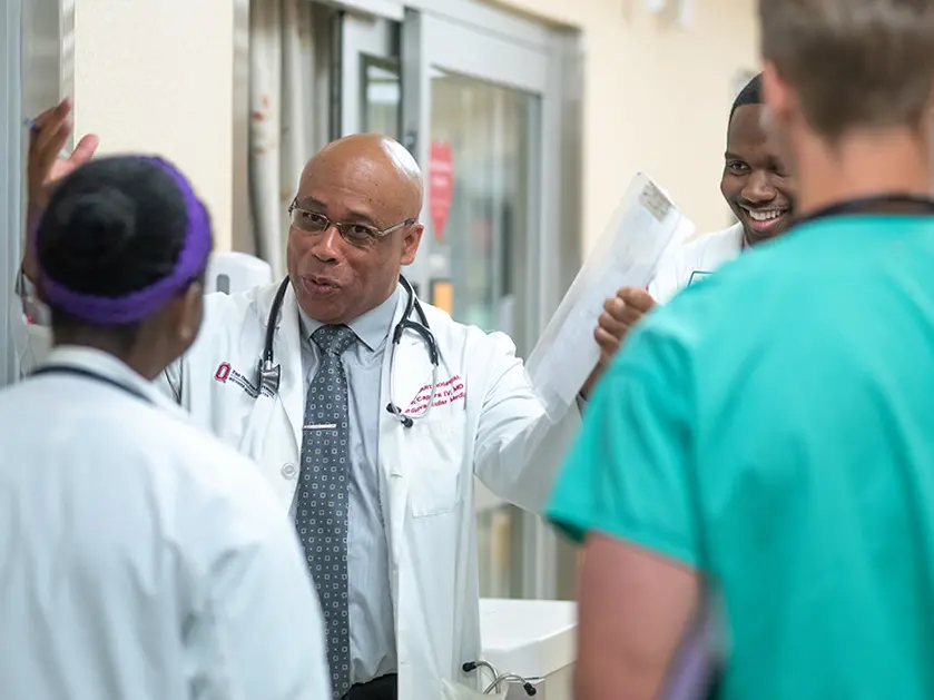 A black doctor in a lab coat jokes with medical students