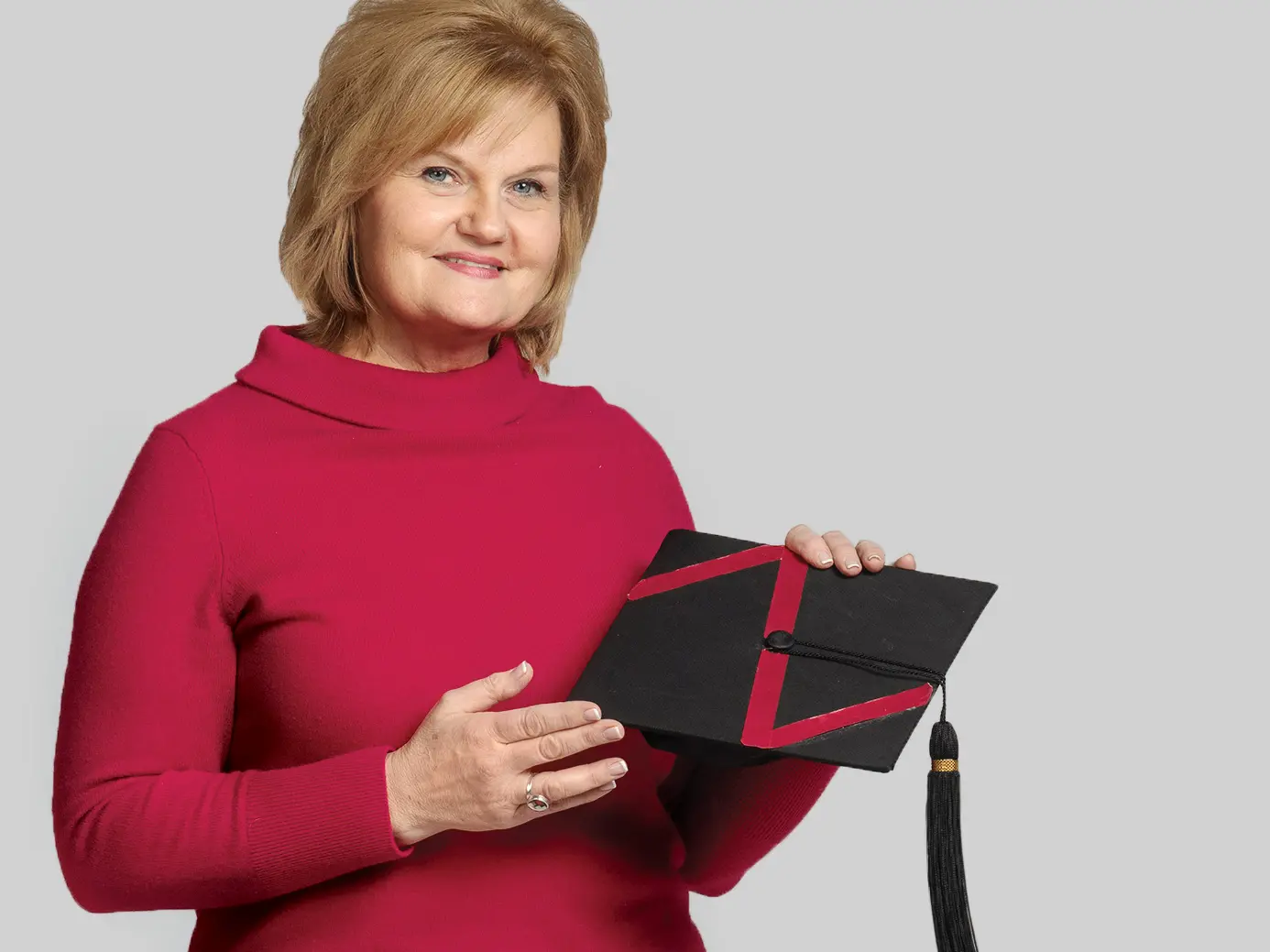 A smiling woman wears red and holds a mortarboard