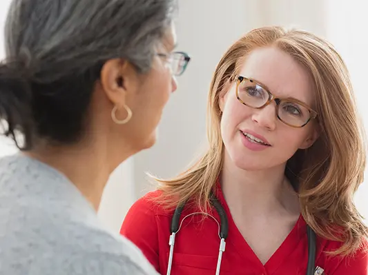 A young doctor tilts her head anA young doctor tilts her head and with direct eye contact listens intently to an older woman speaking to herd listens intently to an older woman speaking to her