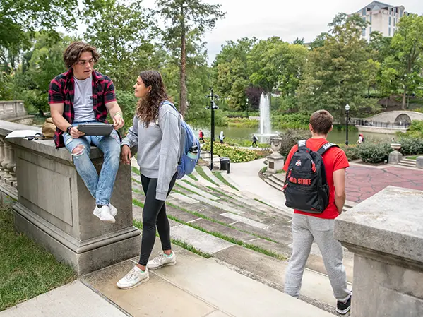 Two students with a laptop talk between classes atop Browning Amphitheater with Mirror Lake n the near distance