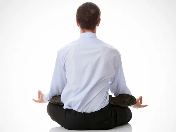 A man with his back to the viewer sits in a seated yoga position