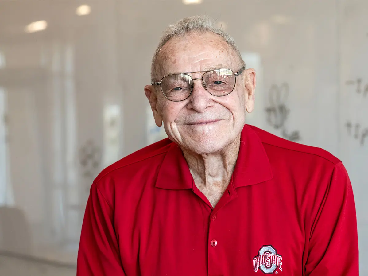 An older white man in an Ohio State shirt smiles broadly.