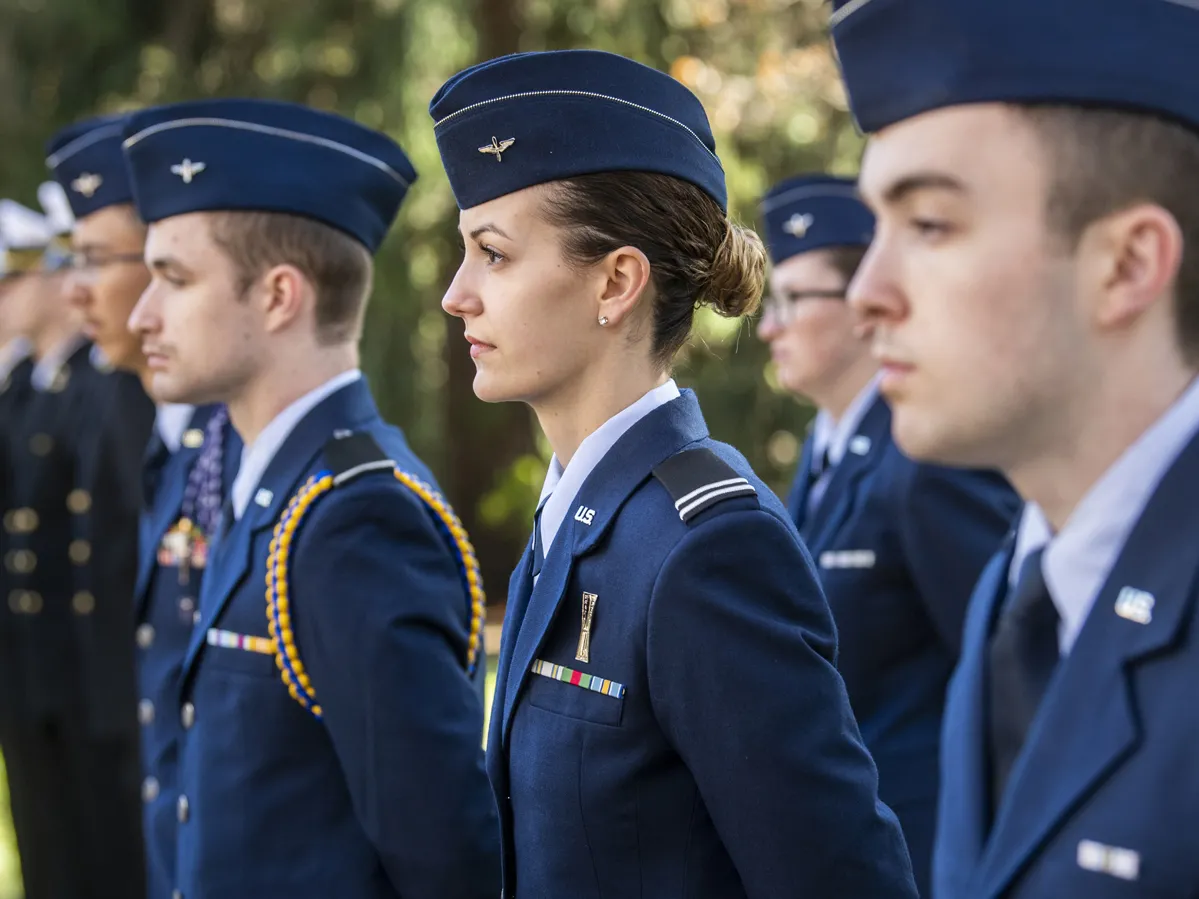 ROTC students at Ohio State stand in a line at attention in their uniforms and hats. They’re outside on an early fall day when the sun is shining brightly.