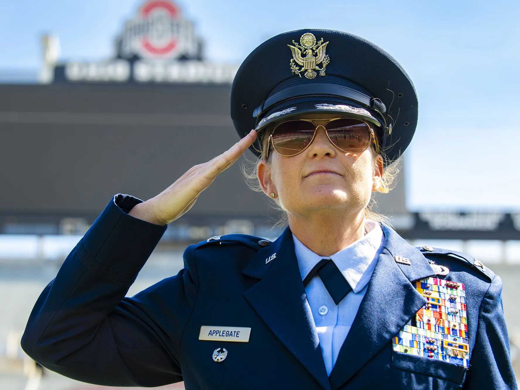 An AIr Force colonel in full dress uniform salutes as she looks slightly upward, creating a portrait that conveys her happiness and power.