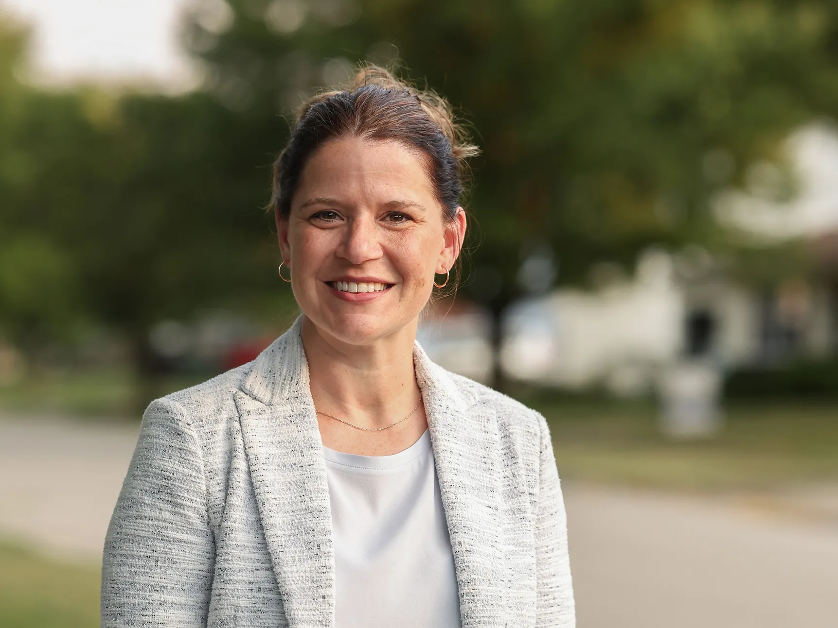 Stephanie Mouton, a friendly-looking brunette with her hair pulled back, wears a sport coat over a T-shirt as she poses on a street with houses for sale. She’s a white woman who looks younger than she probably is given her expertise and knowledge base.