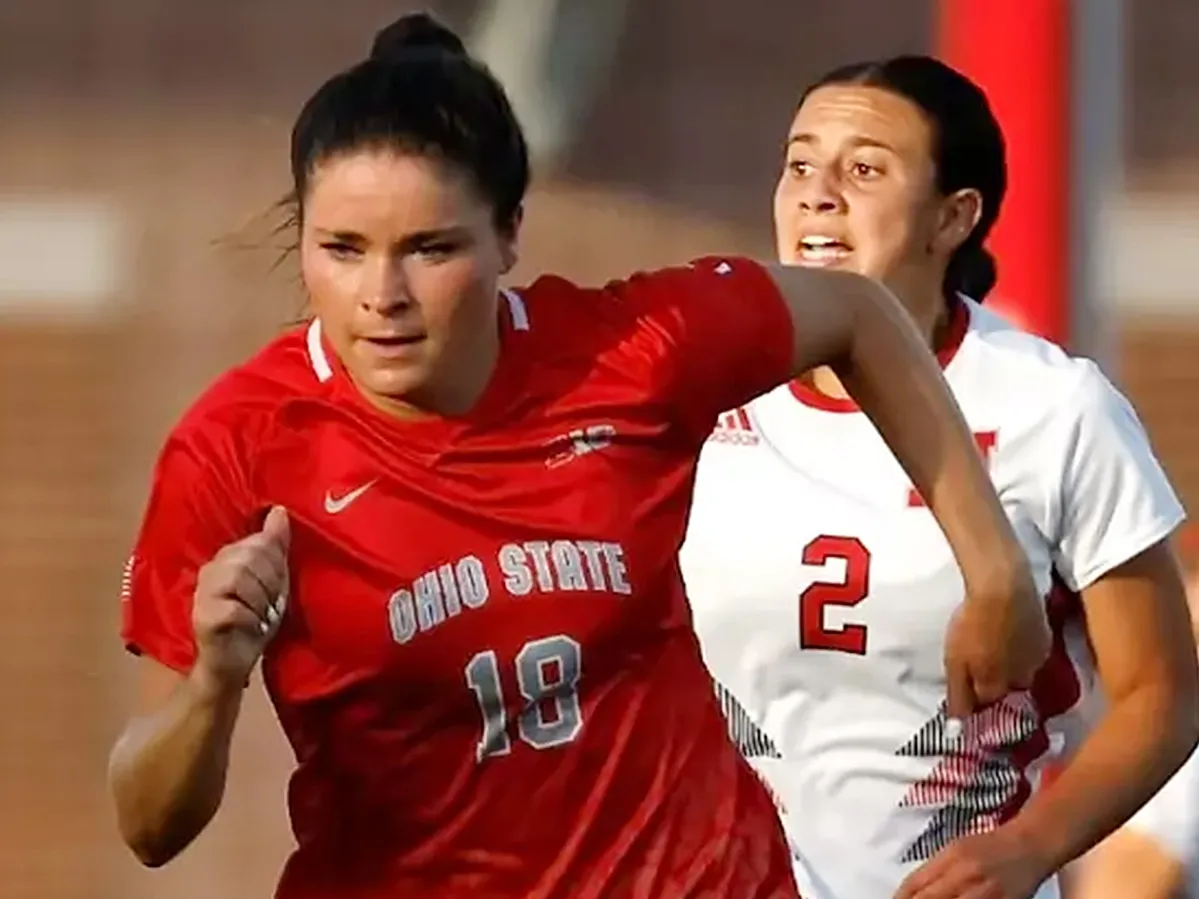 Wearing an Ohio State uniform and a determined expression, Emma Sears sprints to the soccer ball, outpacing her opponent. Sears is a young white woman. 