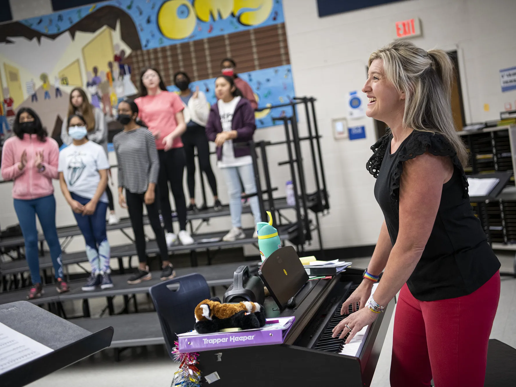 Katie Silcott plays electric piano in her classroom surrounded by students singing