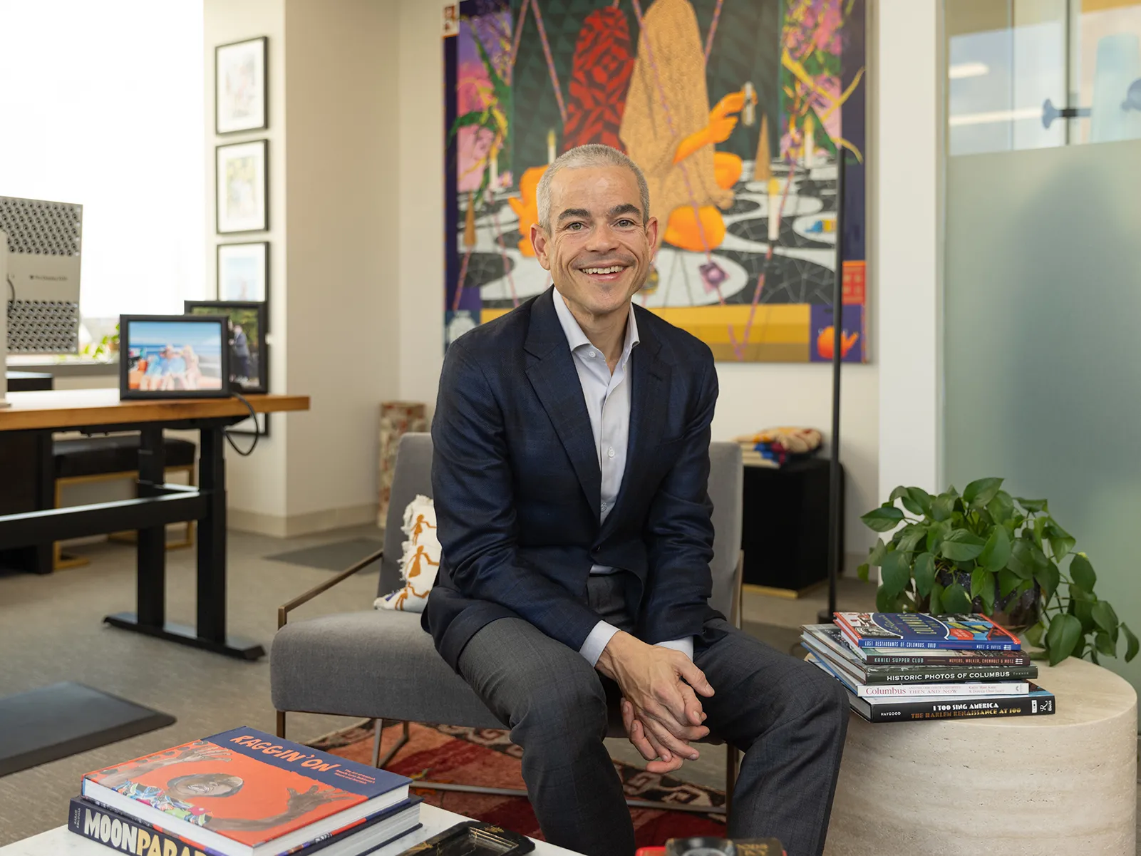 Matt Scantland smiles as he poses for a portrait in his office. He's a thin, white, middle age man with close cropped hair wearing a sportcoat. His smile is genuine.