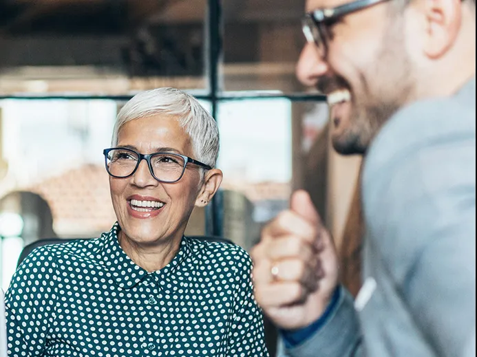 People chat in a work setting. They all look happy to be together.