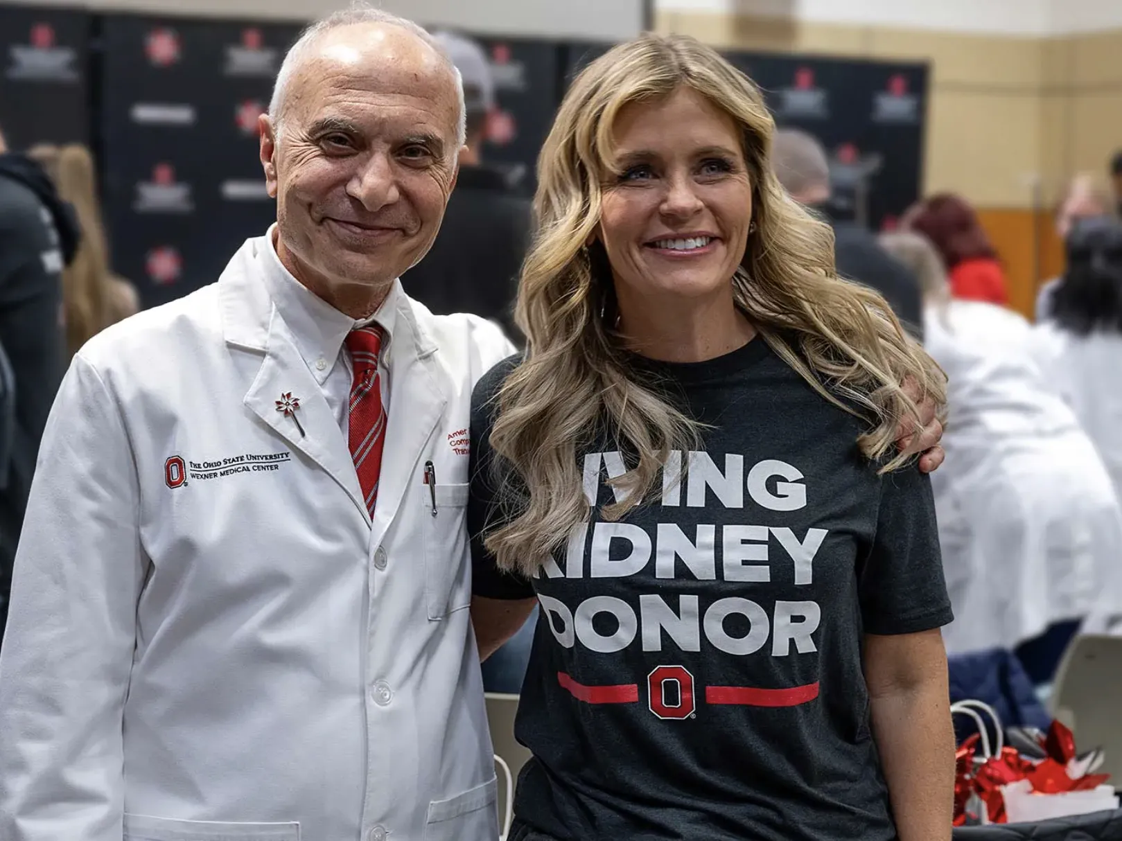 A doctor in his white coat and a donor wearing a T-shirt that says "Living kidney donor" smile as they pose for a photo.