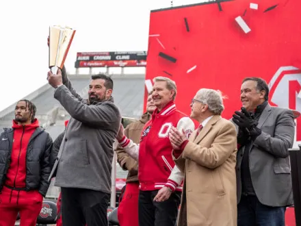 Coach Ryan Day lifts the national championship trophy as Univeristy President Ted Carter pats his shoulder and Ohio&#039;s governor and Columbus&#039; mayor clap