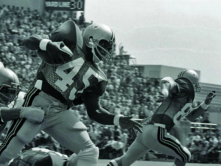 Archie Griffin tries to evade defenseman while carrying the football in a black and white photo from a game