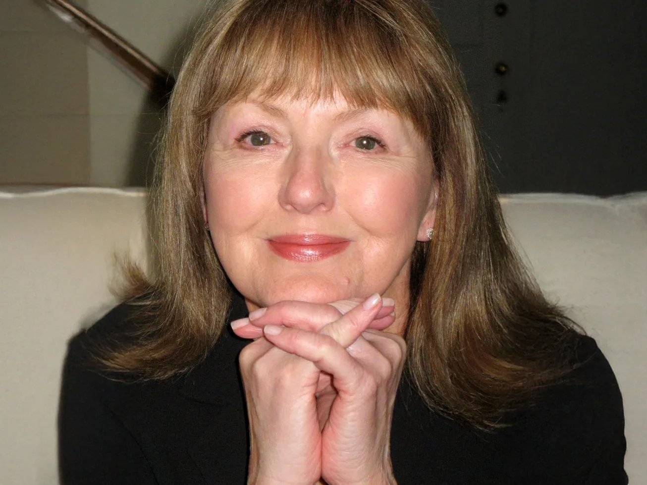 Carole Gerber rests her chin on her clasped hands and softly smiles in this portrait of her.