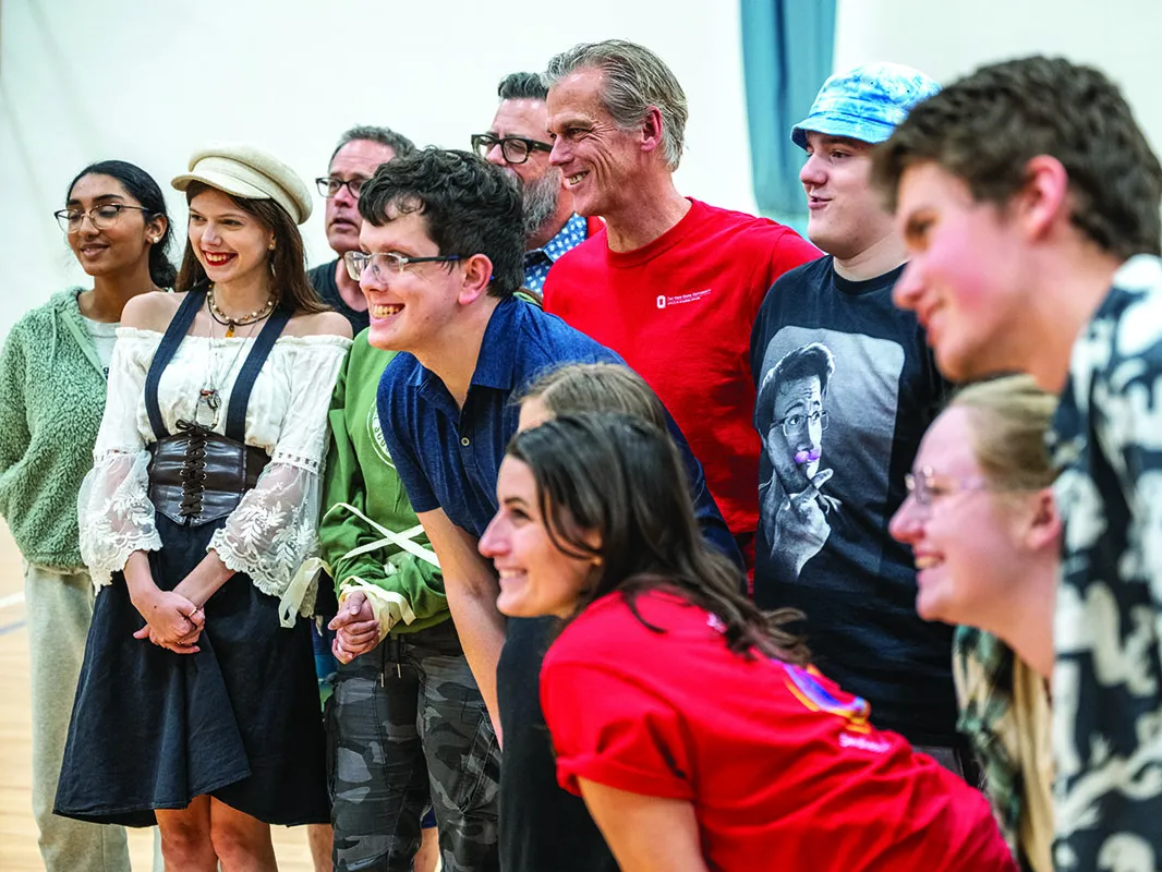 associate professor Kevin McClatchy grins as he poses with teens and college students who took and helped with a Shakespeare in Autism session. Everyone has big smiles.