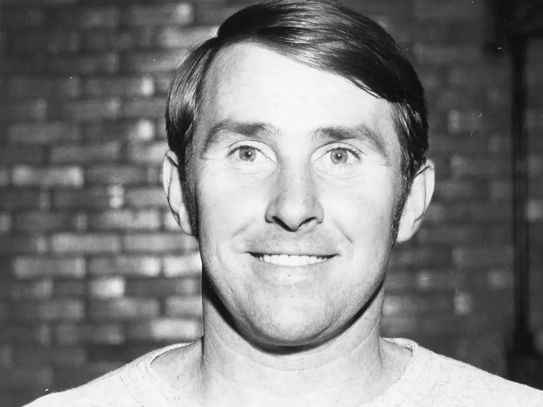 A clean-cut young man, Ron O'Brien smiles for the camera. This is a black and white photo, and he as eyes wide open and wears and Ohio State T-shirt.