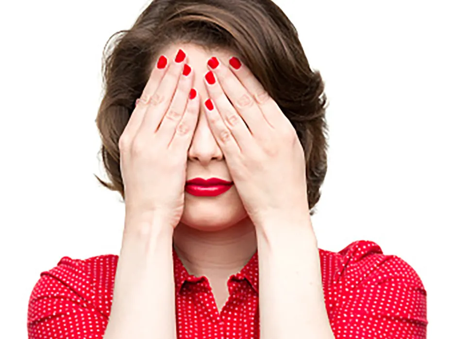 A woman covers her eyes with her hands
