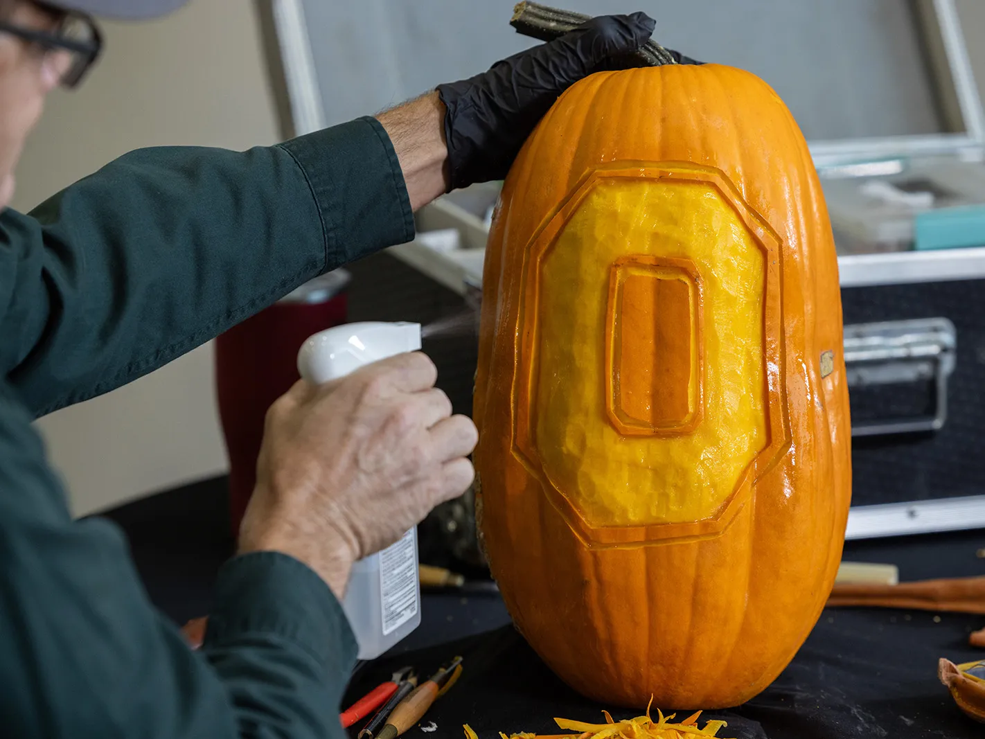 Smithhisler uses a spray bottle full of alcohol to vigorously wet the face of his carved pumpkin.