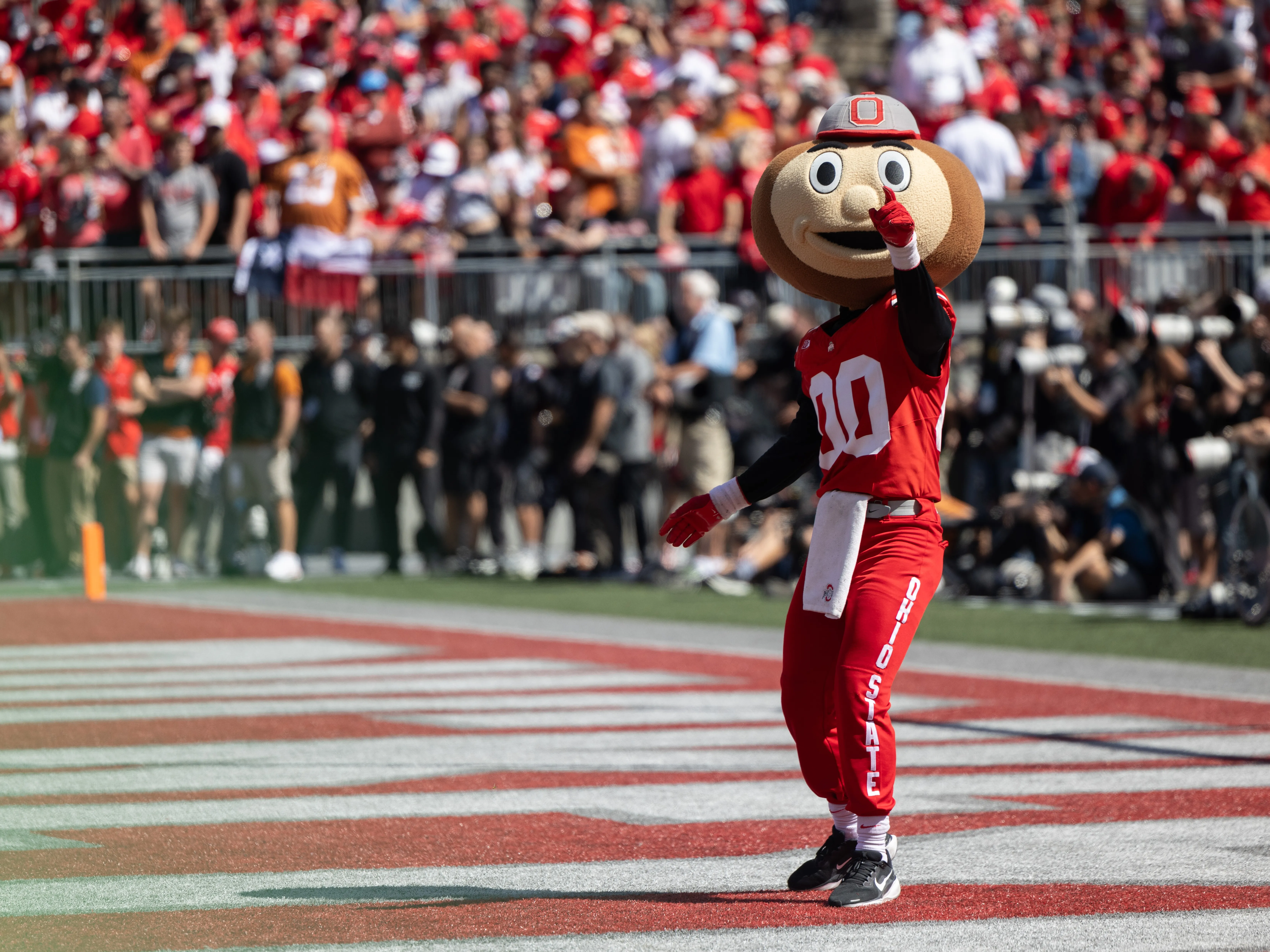 Brutus Buckeye points at the camera on the field before a football game