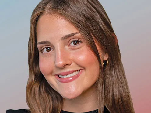 A young woman with long hair smiles as she looks directly into the camera