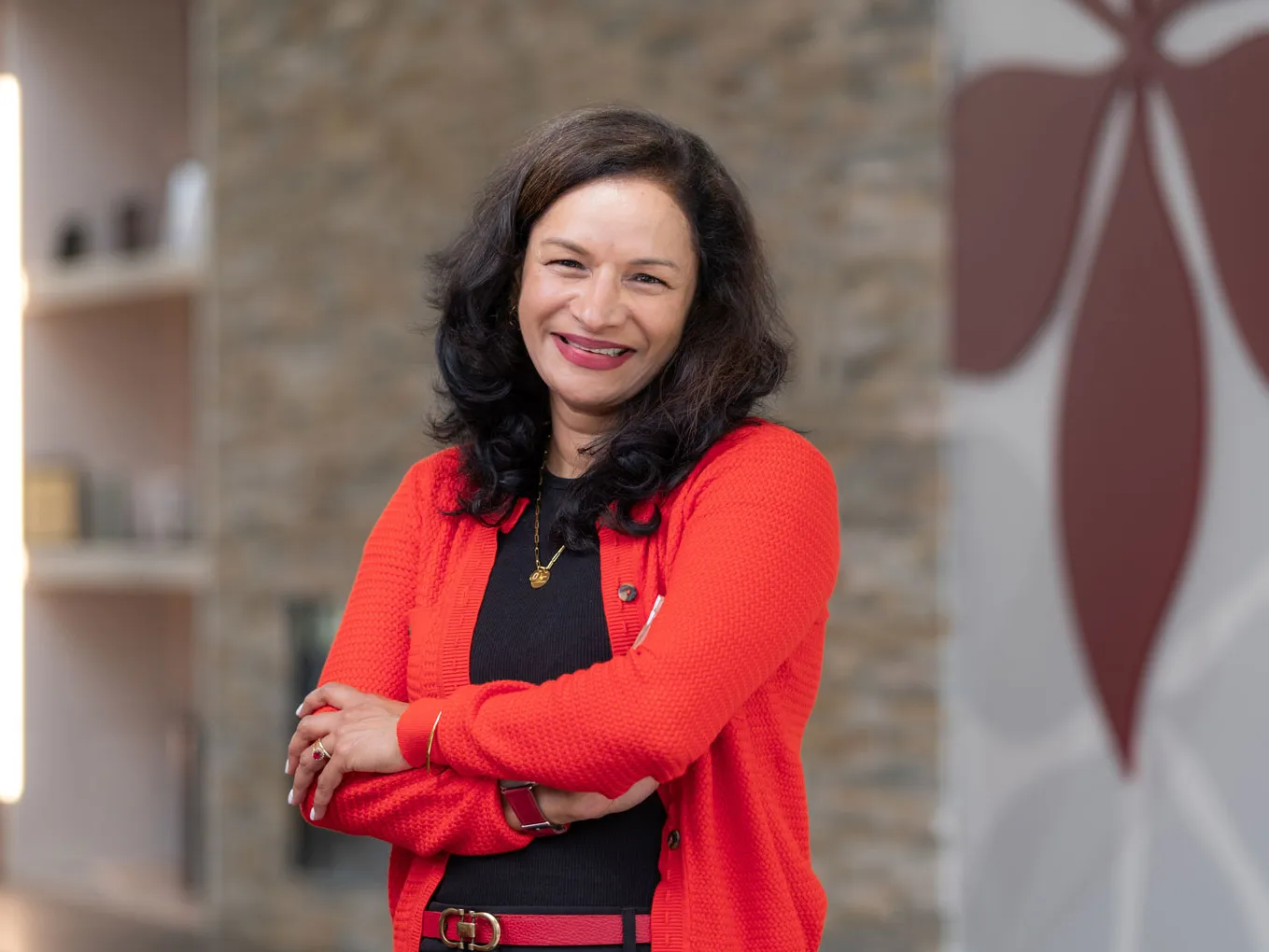 Lalita Kaligotla smiles as she poses for a photo inside an Ohio State building. She has long hair and wears a scarlet cardigan and belt over a dark T-shirt and dress pants. She comes across as both stylish and friendly, like someone you'd want to spend time talking with.