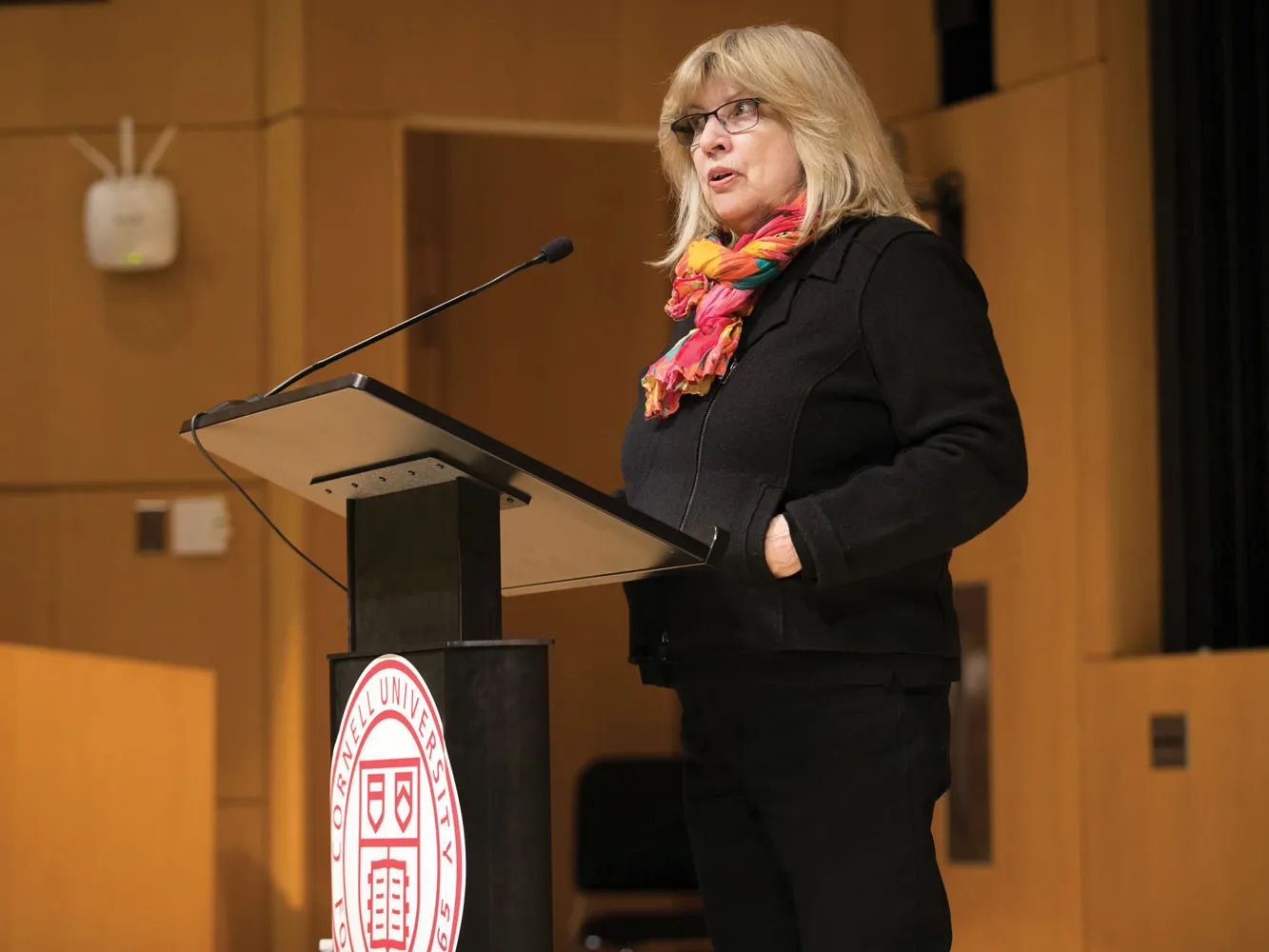 Stephanie Vaughn stands behind a podium, facing slightly to the side as she speaks to an audience or class.
