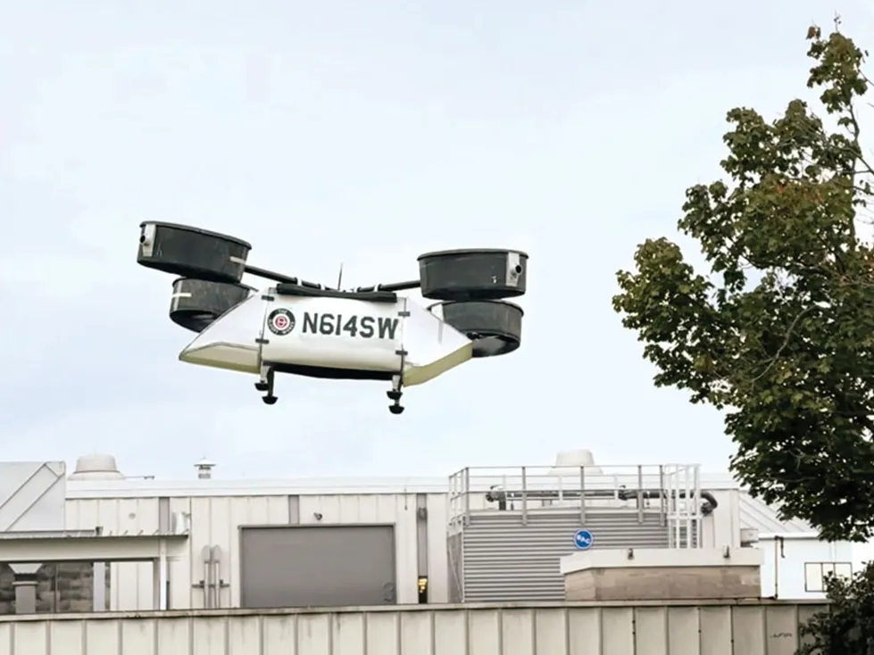 A model rescue drone created at Ohio State flies into the air. It has a large body to ferry people or supplies and 8 propellers enclosed in four cannisters, each at the end of a pole. Together, they're laid out as a helicopter's rotors would be.  