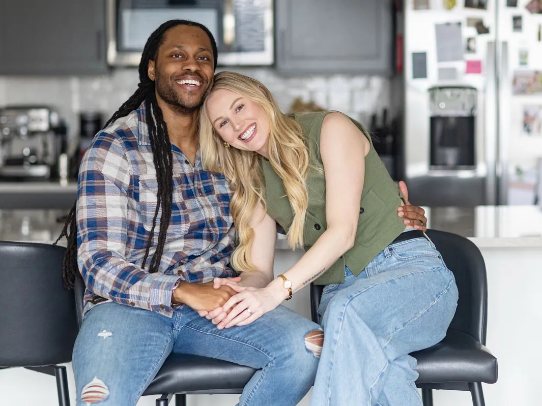 Victor St John and Christine Hamilton pose for a photo in their home. They appear happy as she leans her head on his shoulder.