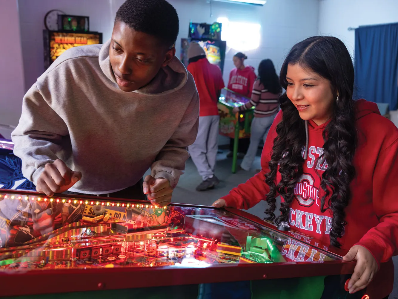 A pair of students have fun playing pinball at the Electric Playground.